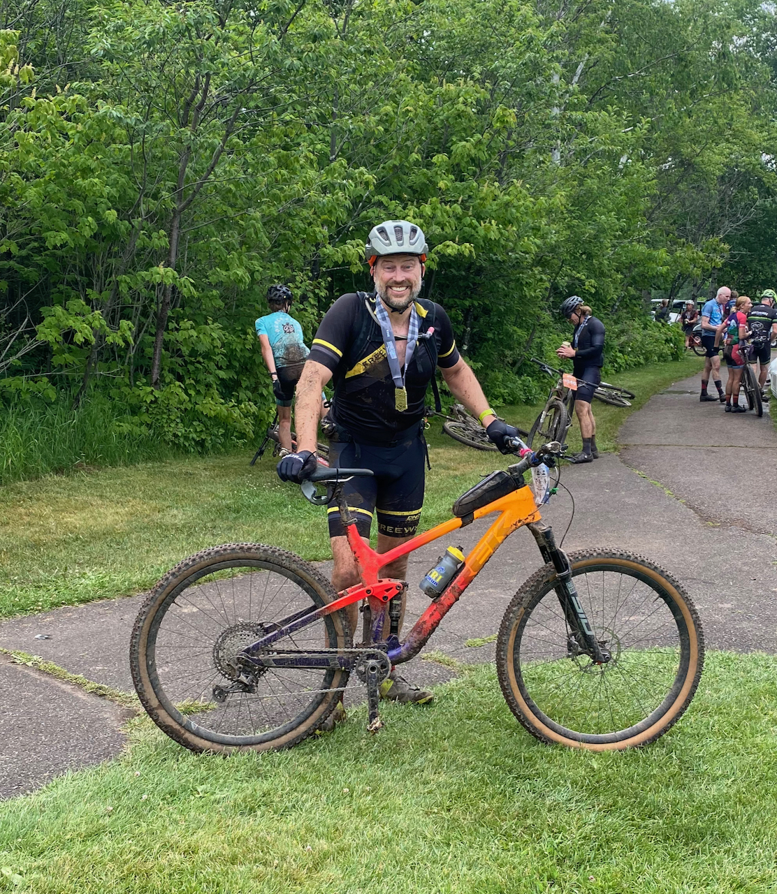 Ken Barringer standing with his mountain bike dirty after a muddy ride