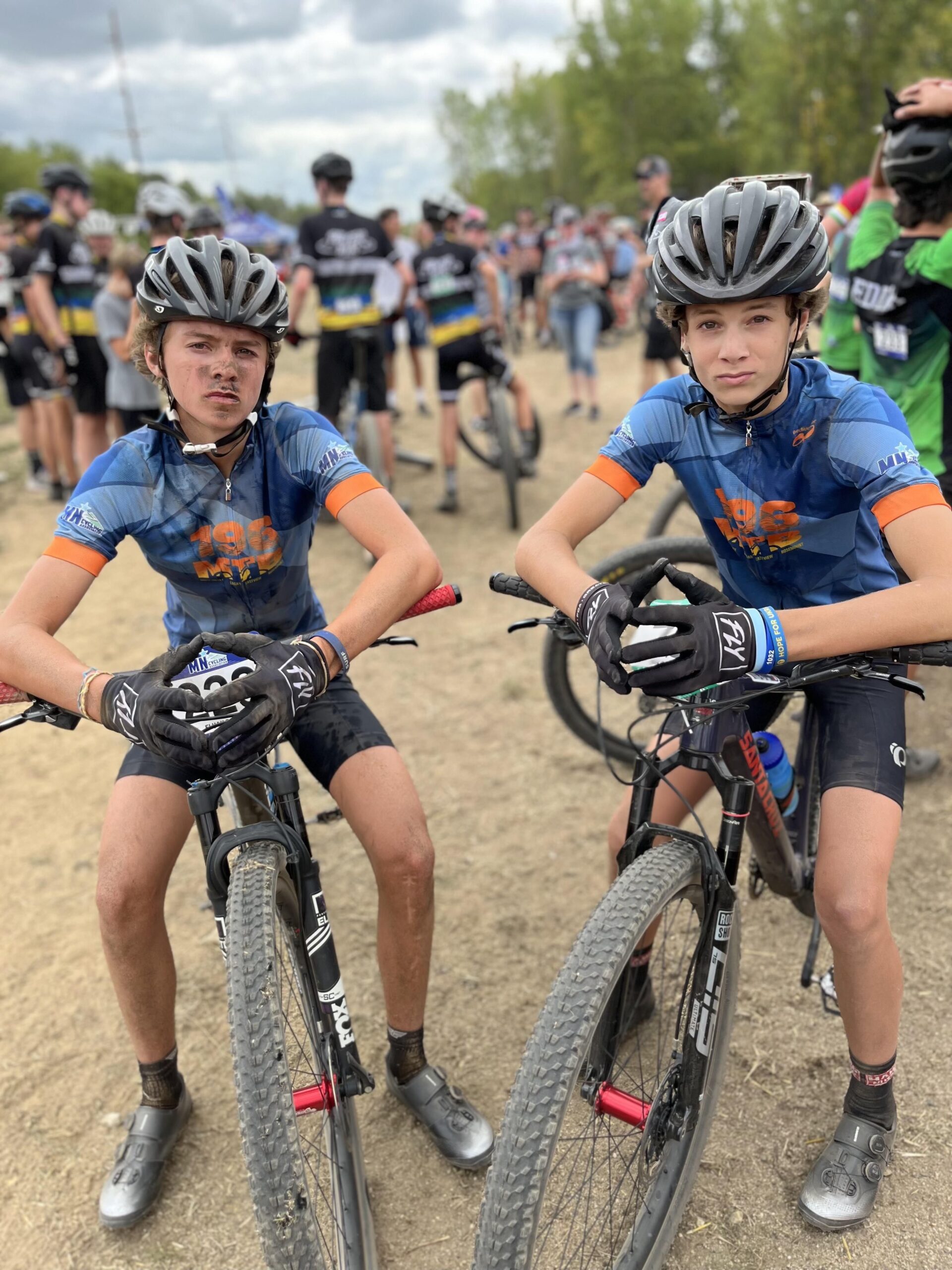 Two boys sitting on their bikes posing in front of the camera after a race